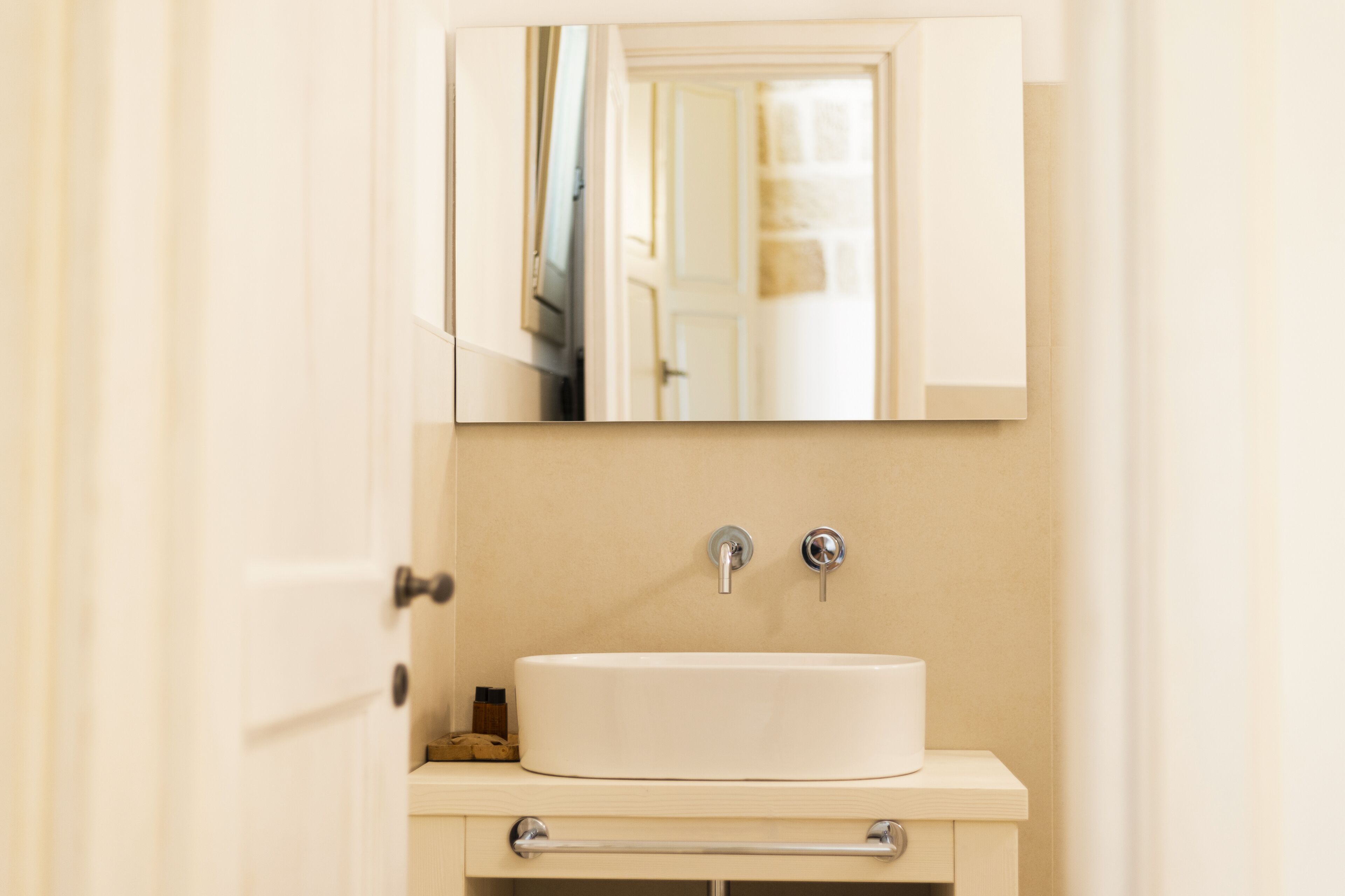 Un baño con un lavamanos blanco, dos grifos y un espejo sobre el lavamanos.