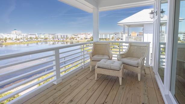 A wooden deck with wicker chairs and a view of a marina and buildings. - Lakefront Oasis w/ panoramic views on private road (Carolina Beach)