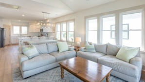 A spacious living room with a large sectional sofa, a wooden coffee table, and a kitchen in the background. - Lakefront Oasis w/ panoramic views on private road (Carolina Beach)