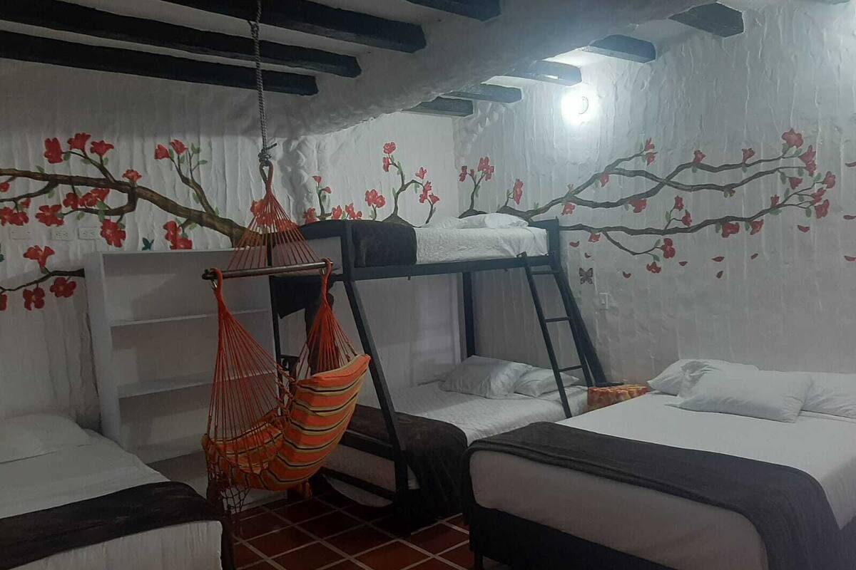Un dormitorio con literas, una hamaca y decoración floral en las paredes.