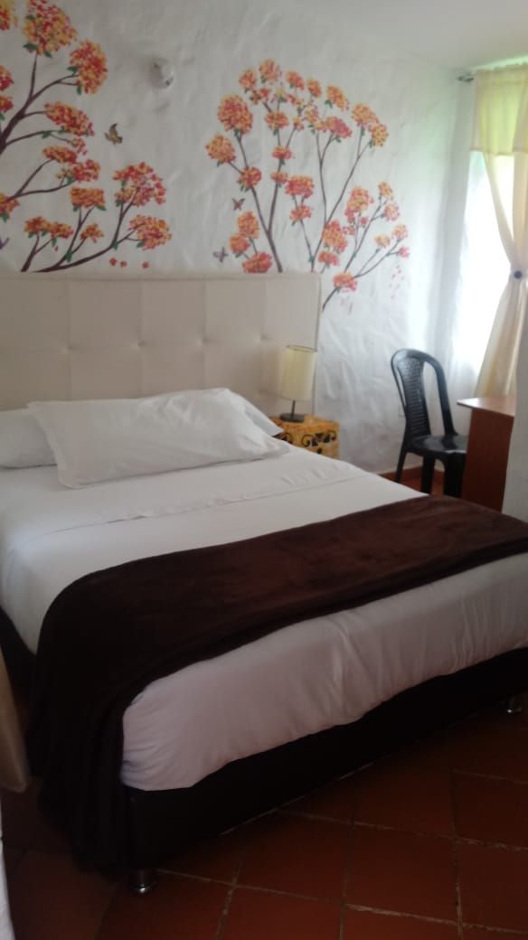 A bedroom with a bed, a nightstand, a chair, and a wall with floral patterns.