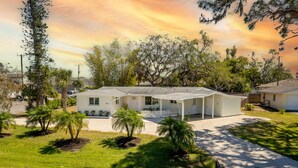 A single-story house with a covered porch, surrounded by a well-maintained lawn and trees. - The Lemon Bay Getaway (Venice)