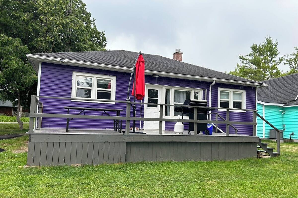 A two-story house with a purple exterior and a grey deck.