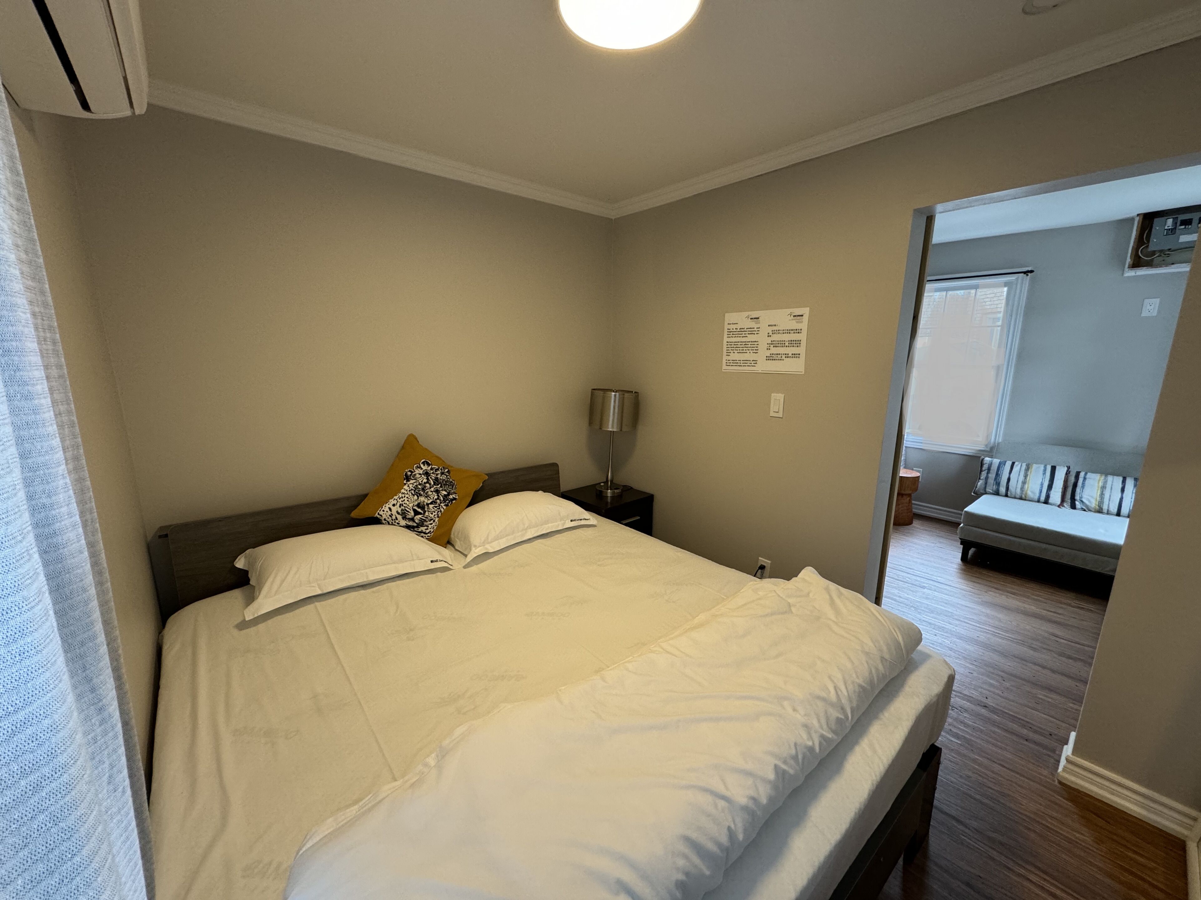 Une chambre à coucher avec un lit, une table de chevet, une lampe et une fenêtre.