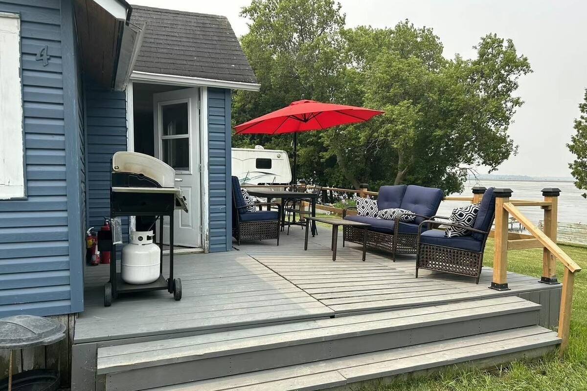 A deck with outdoor furniture, a grill, and a red umbrella.