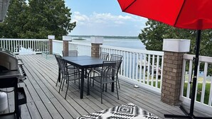 Eine Terrasse mit Tisch, Stühlen, einem Grill und einem roten Sonnenschirm.
