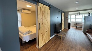 Ein Zimmer mit Bett, Holzschrank, Fernseher und einer Bank.
