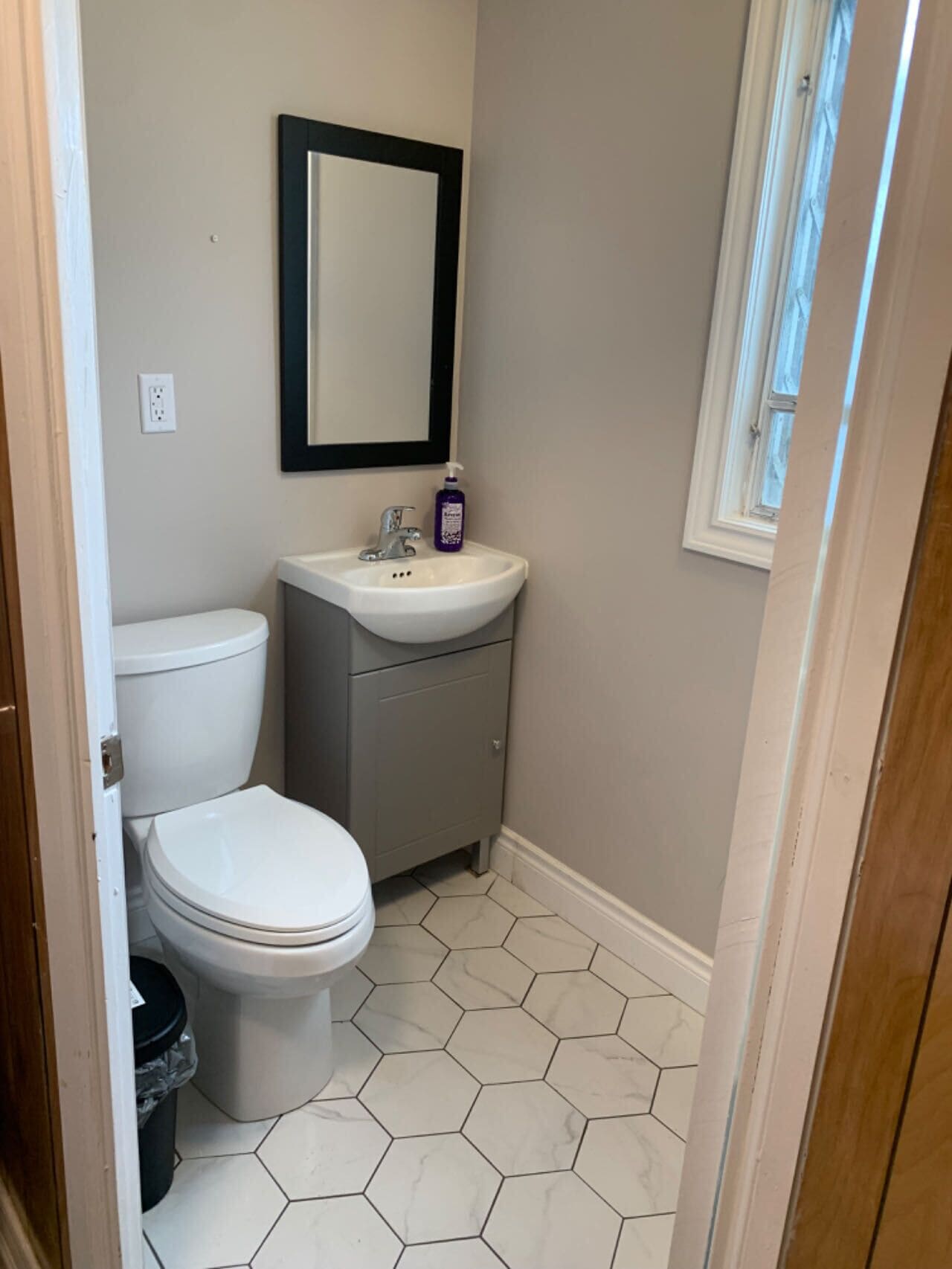 A small bathroom with a toilet, sink, and mirror.