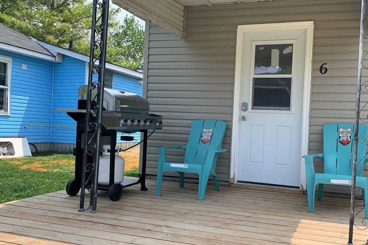 A porch with a grill, two chairs, and a door marked with the number 6.