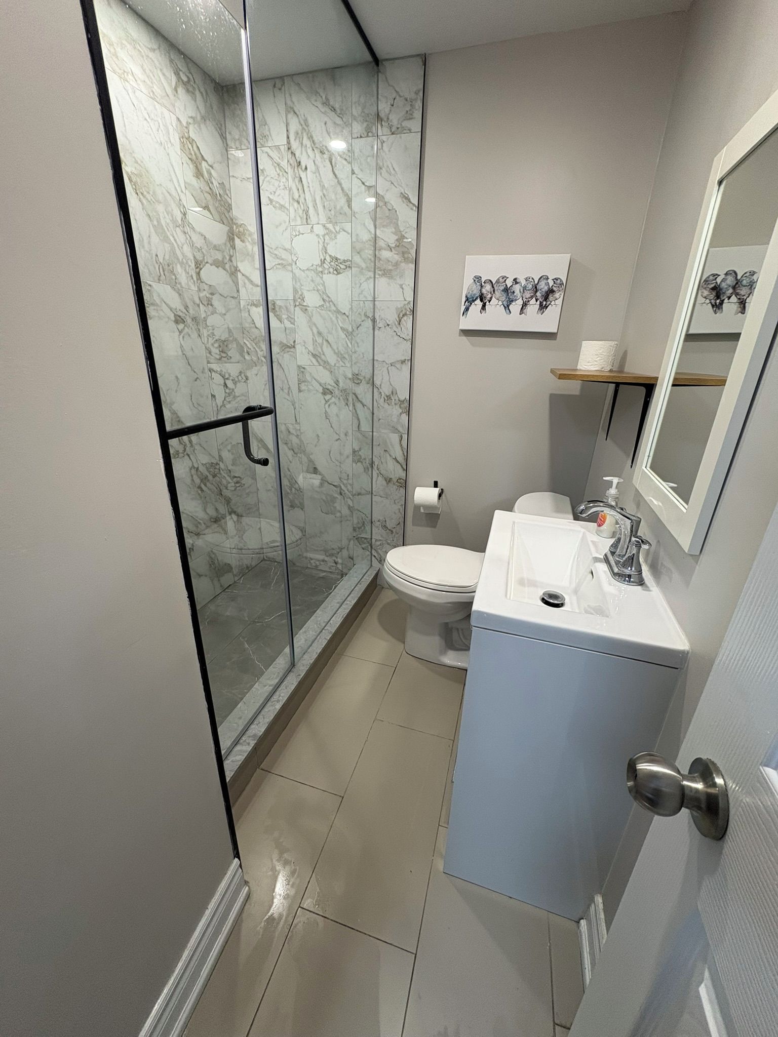 Un baño con cabina de ducha de vidrio, inodoro y lavabo con espejo.