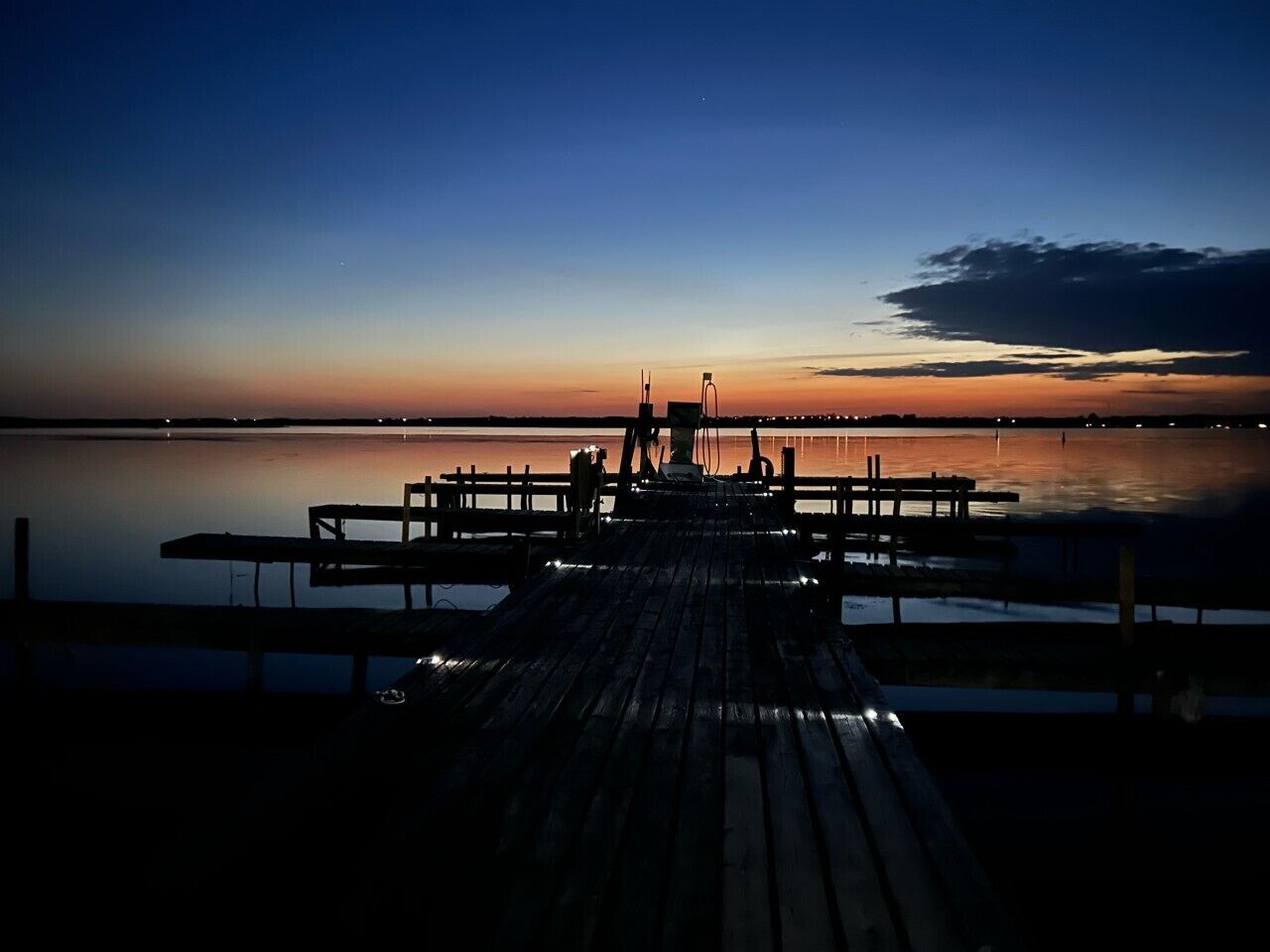 Un muelle de madera que se adentra en aguas tranquilas al anochecer.