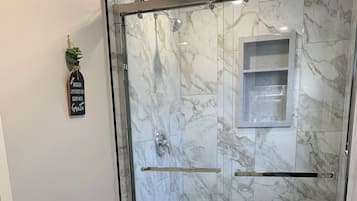 Un baño moderno con ducha de vidrio, inodoro y lavamanos.
