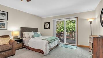 Un dormitorio con cama, mesita de noche, lámpara, cómoda y vistas a una terraza exterior por medio de una puerta corrediza de vidrio.