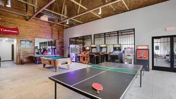 A spacious indoor area with a ping pong table, pool table, and arcade machines.
