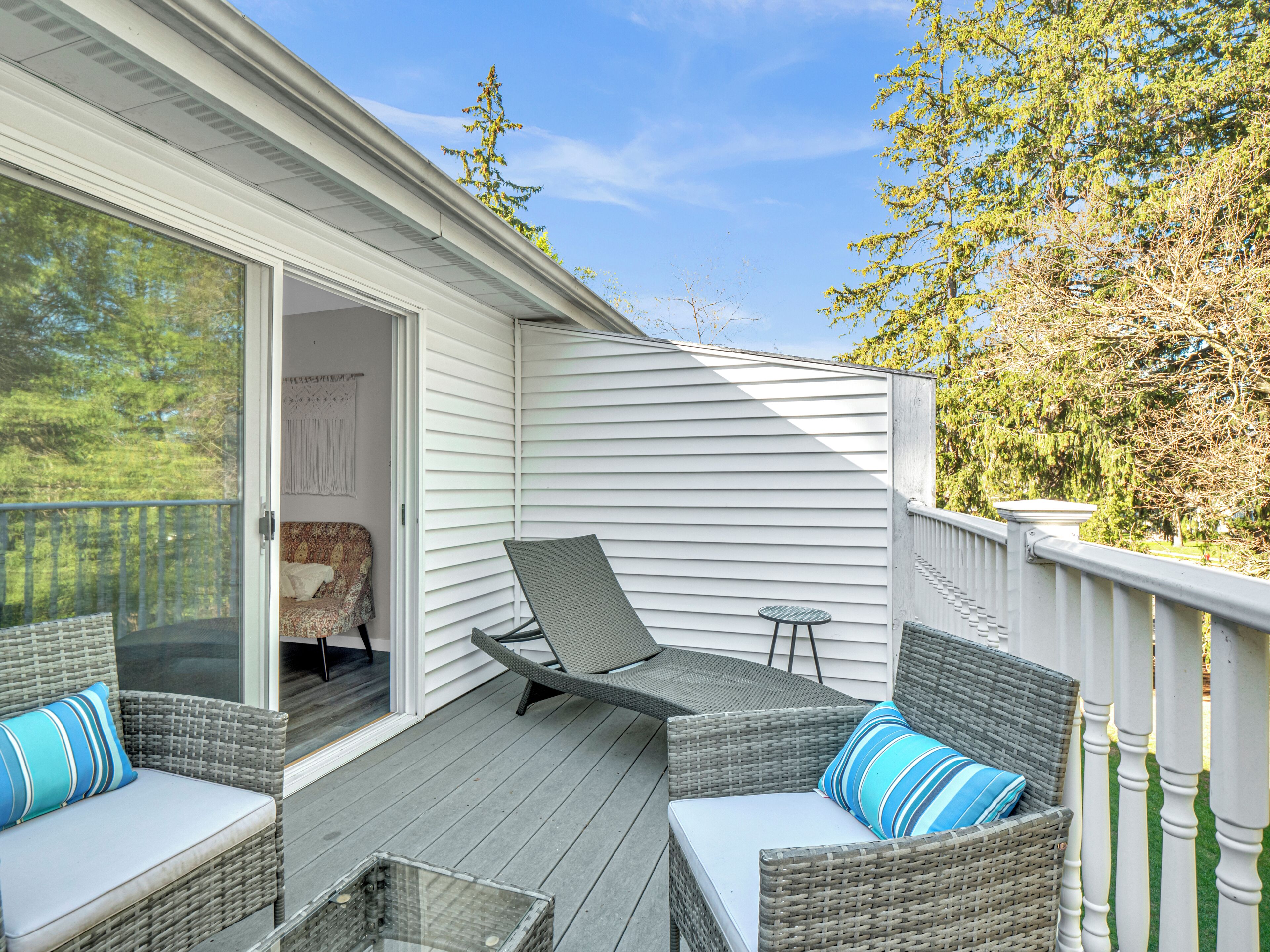 A covered deck with wicker furniture and a sliding glass door leading to a bedroom.
