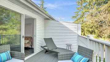 A covered deck with wicker furniture and a sliding glass door leading to a bedroom.