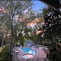 Un área de piscina con sillas de descanso y un edificio al fondo.