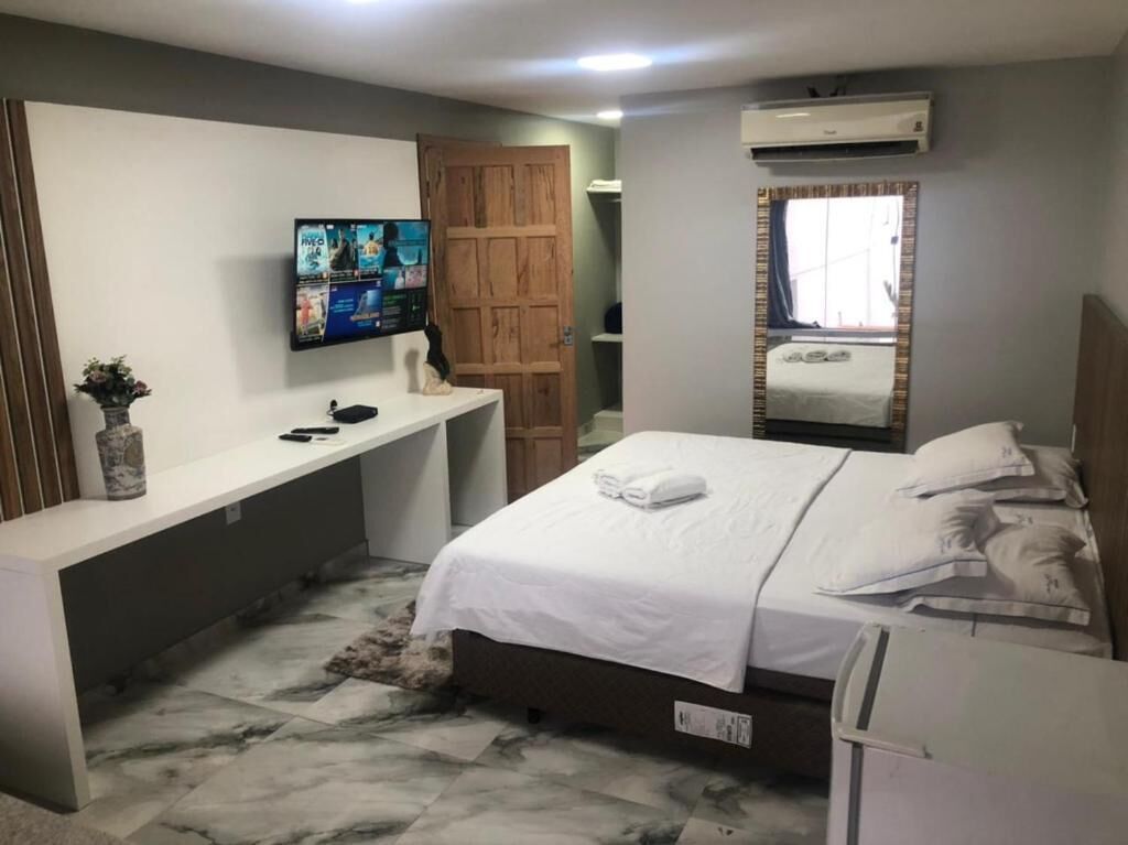 A hotel room with a bed, a desk, a television, and a wardrobe.