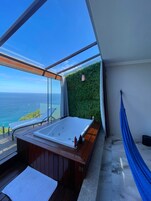 Un balcón con un jacuzzi, una hamaca y vistas al océano.