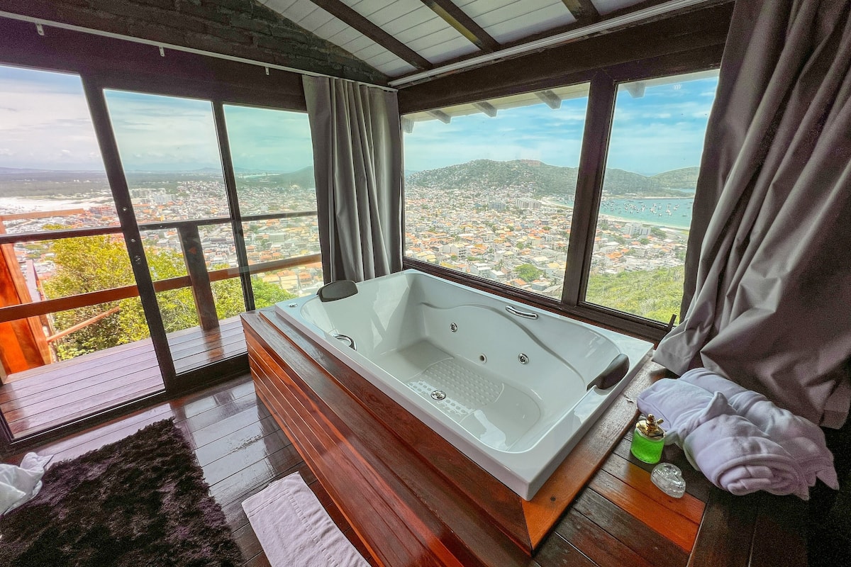 Un bagno moderno con una vasca da bagno spaziosa, pavimento in legno e vista sulla città attraverso ampie finestre.