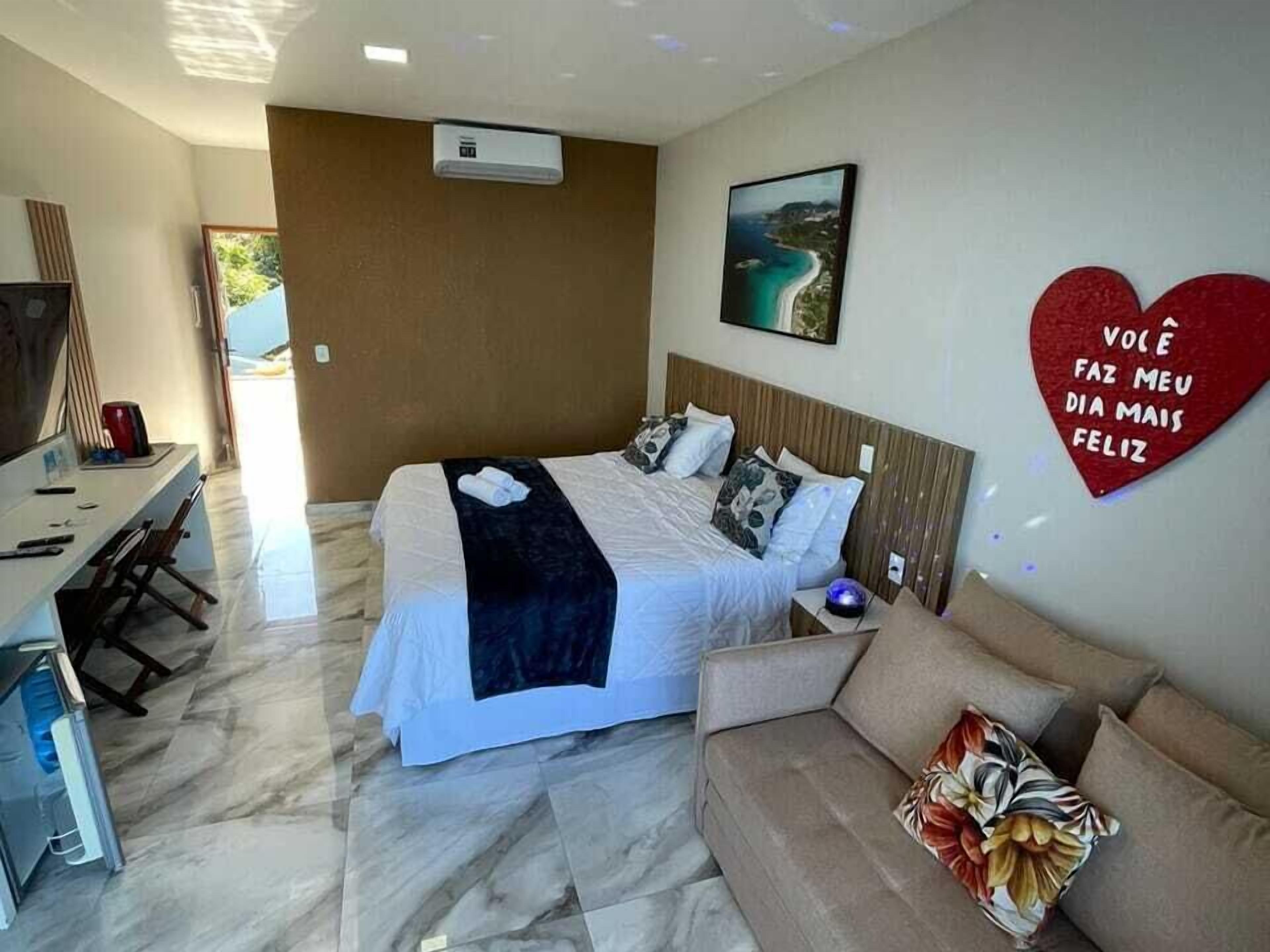 Ein Hotelzimmer mit Bett, Schreibtisch, Sofa und einer herzförmigen Dekoration an der Wand.