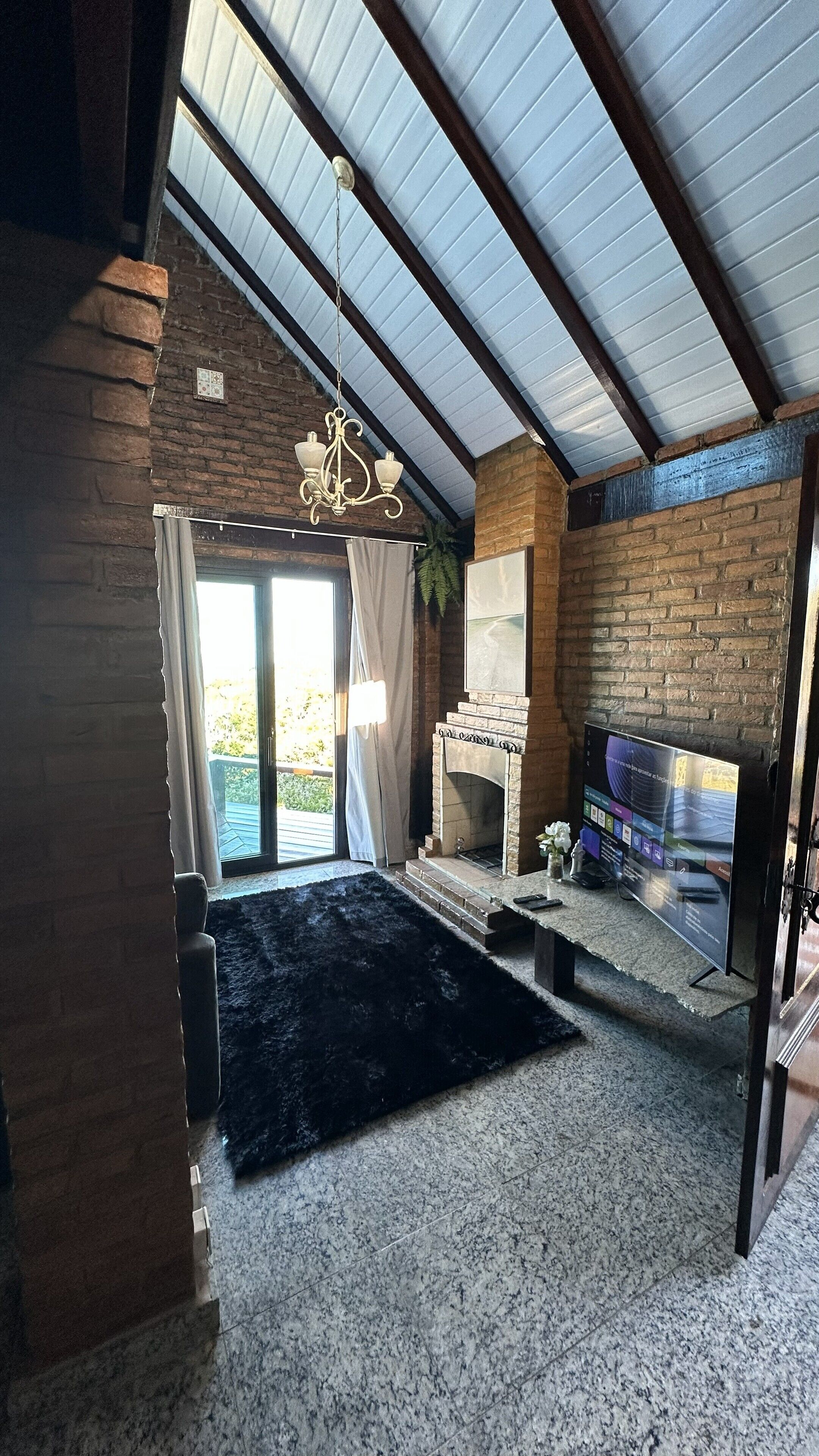 A spacious living room with a high ceiling, a fireplace, and a large window.