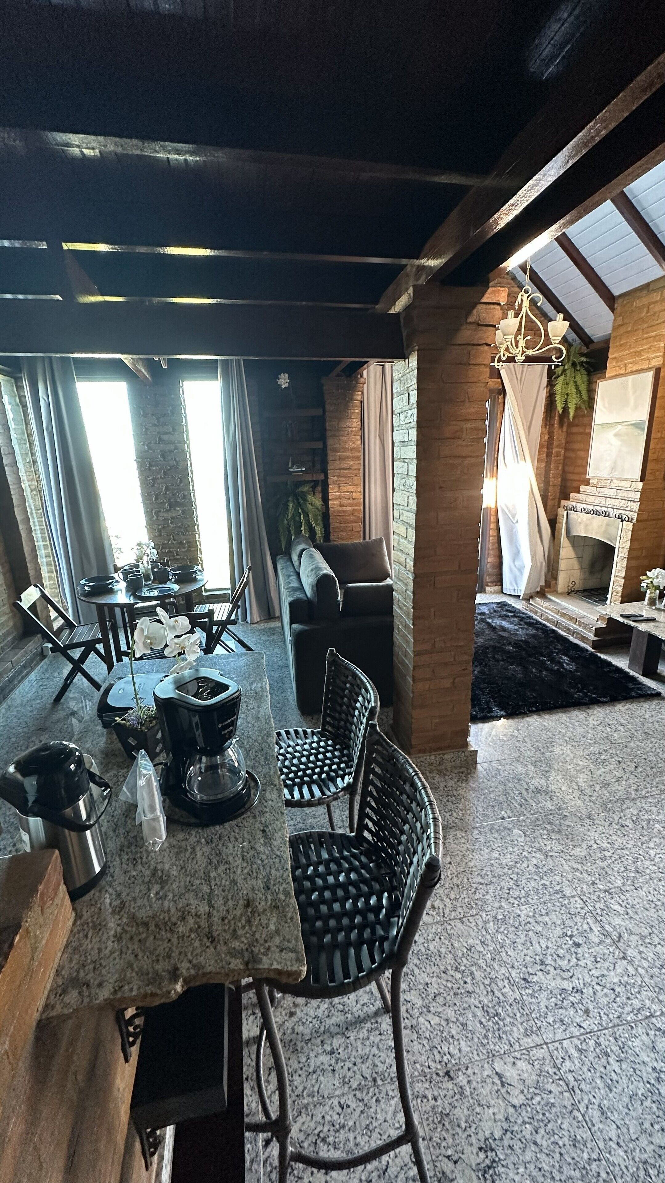 Un coin repas chaleureux avec une cheminée en pierre, un espace dédié au café et une vue sur l’extérieur.