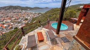 Une terrasse sur le toit avec une piscine, des chaises longues et une vue sur une ville côtière.