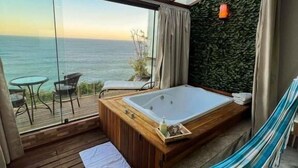 Une pièce dotée d’une terrasse en bois, d’une grande fenêtre donnant sur la mer, d’une baignoire en bois et d’un hamac.