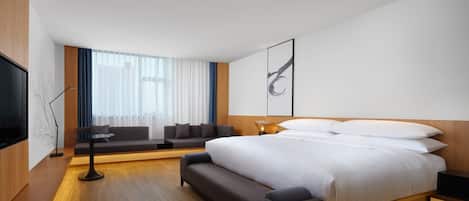 Una habitación de hotel moderna con una cama grande, un sofá, un televisor y un escritorio.