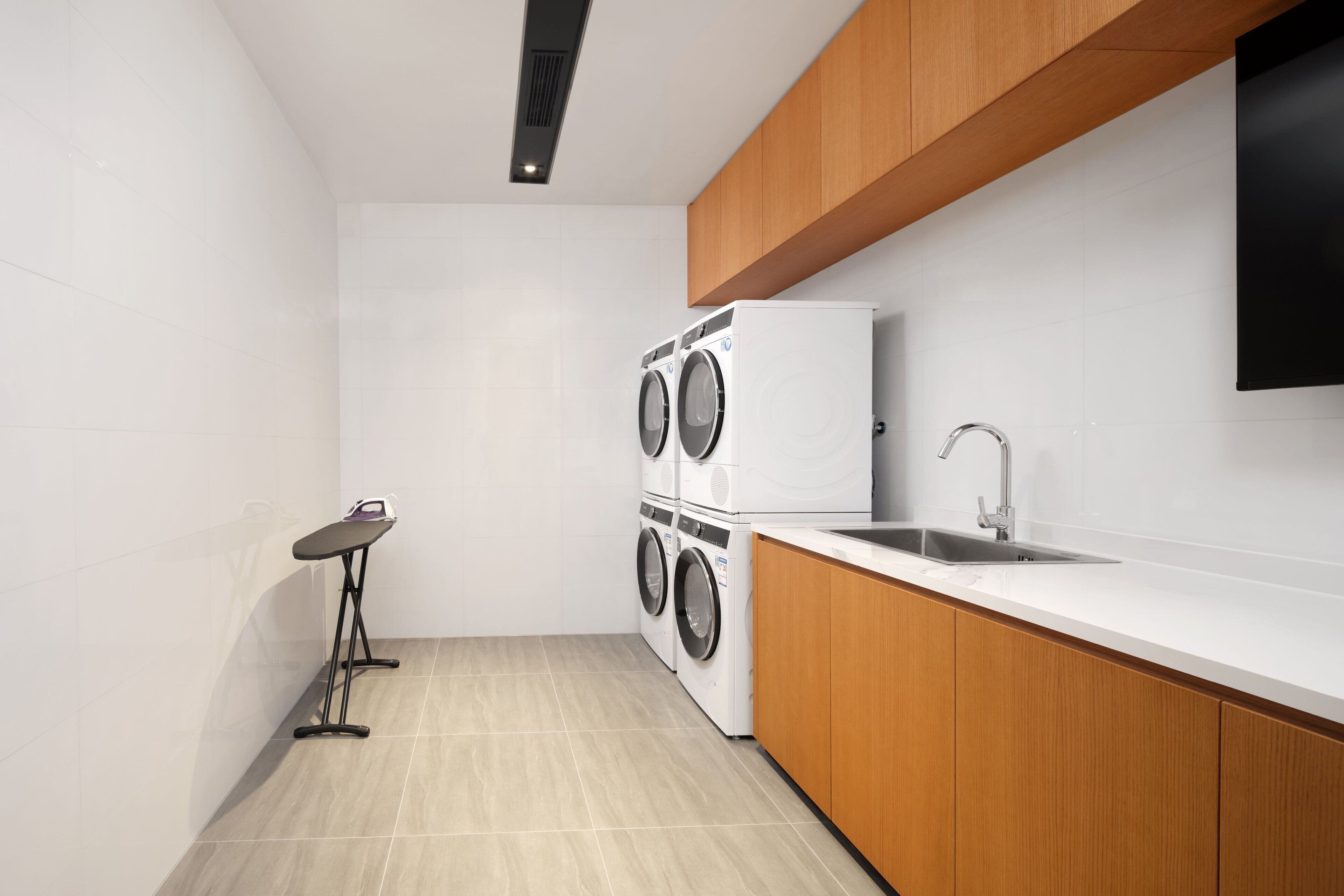 Cocina compacta con lavadora y secadora integradas, una mesita y un lavabo.