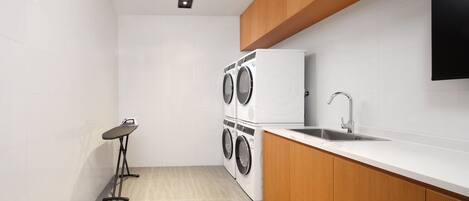 Cocina compacta con lavadora y secadora integradas, una mesita y un lavabo.