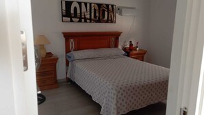 Ett sovrum med en säng, ett nattduksbord, en lampa och en väggmonterad skylt med texten ”LONDON”.