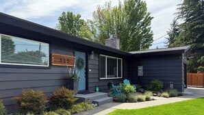 A modern house with a dark exterior, a blue door, and a number 315 sign.