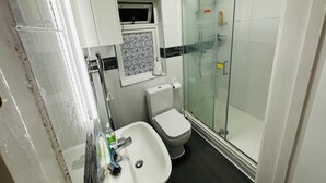 A bathroom with a glass-enclosed shower, a white sink, and a toilet. - Immaculate 1-bed Apartment in Harrow (Harrow)