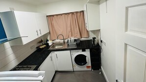 A compact kitchen with a washing machine, a sink, and a stove. - Immaculate 1-bed Apartment in Harrow (Harrow)