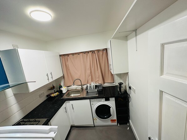 Una cocina compacta con lavadora, un lavabo y una estufa.
