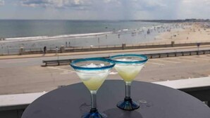 Zwei Martini-Gläser auf einem Tisch mit Blick auf einen Strand und das Meer.