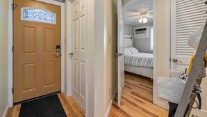Ein Flur, der zu einem Schlafzimmer mit Bett, Deckenventilator und Fenster führt.