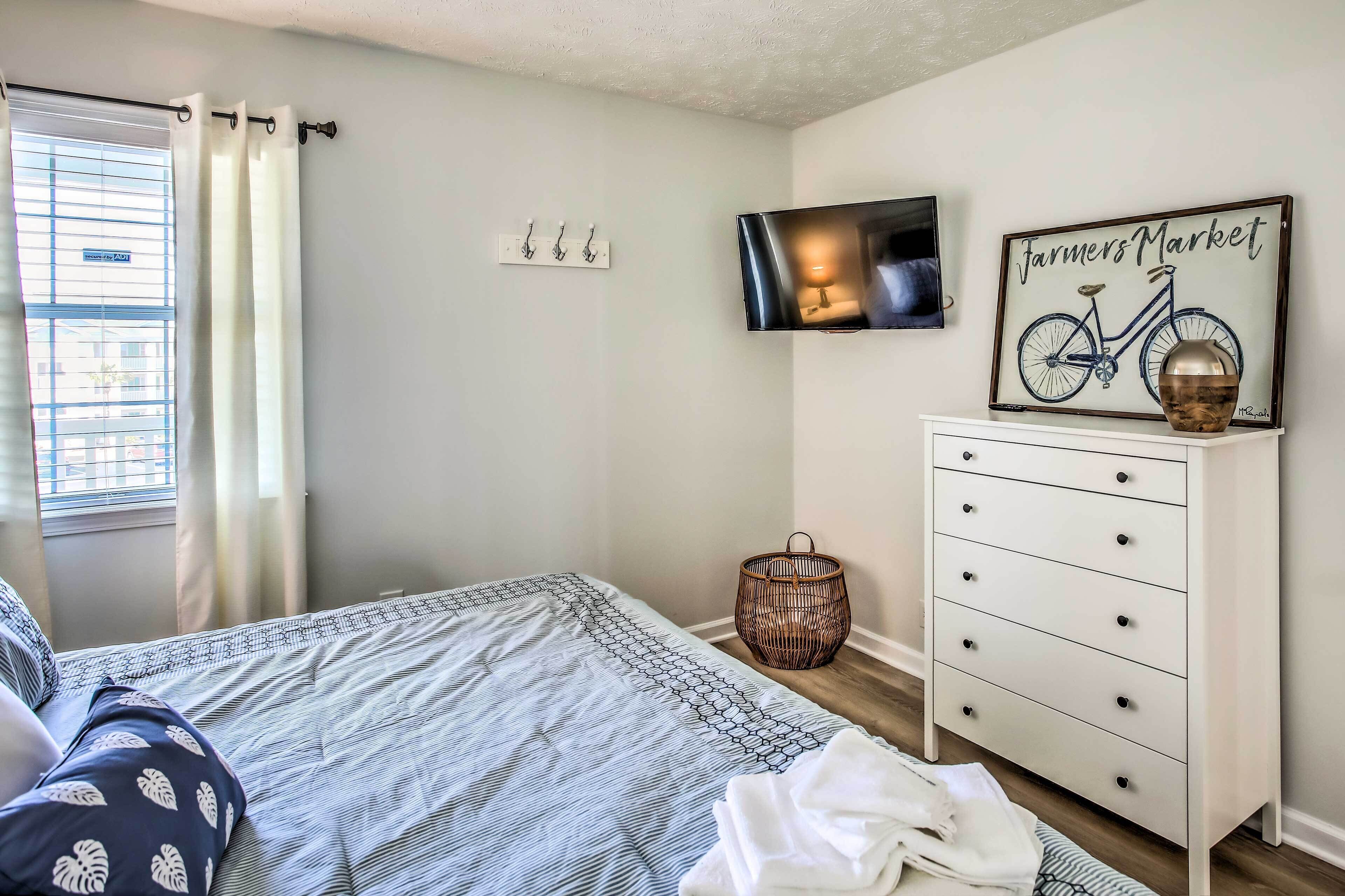 A bedroom with a bed, a dresser, a television, and a wall-mounted picture.
