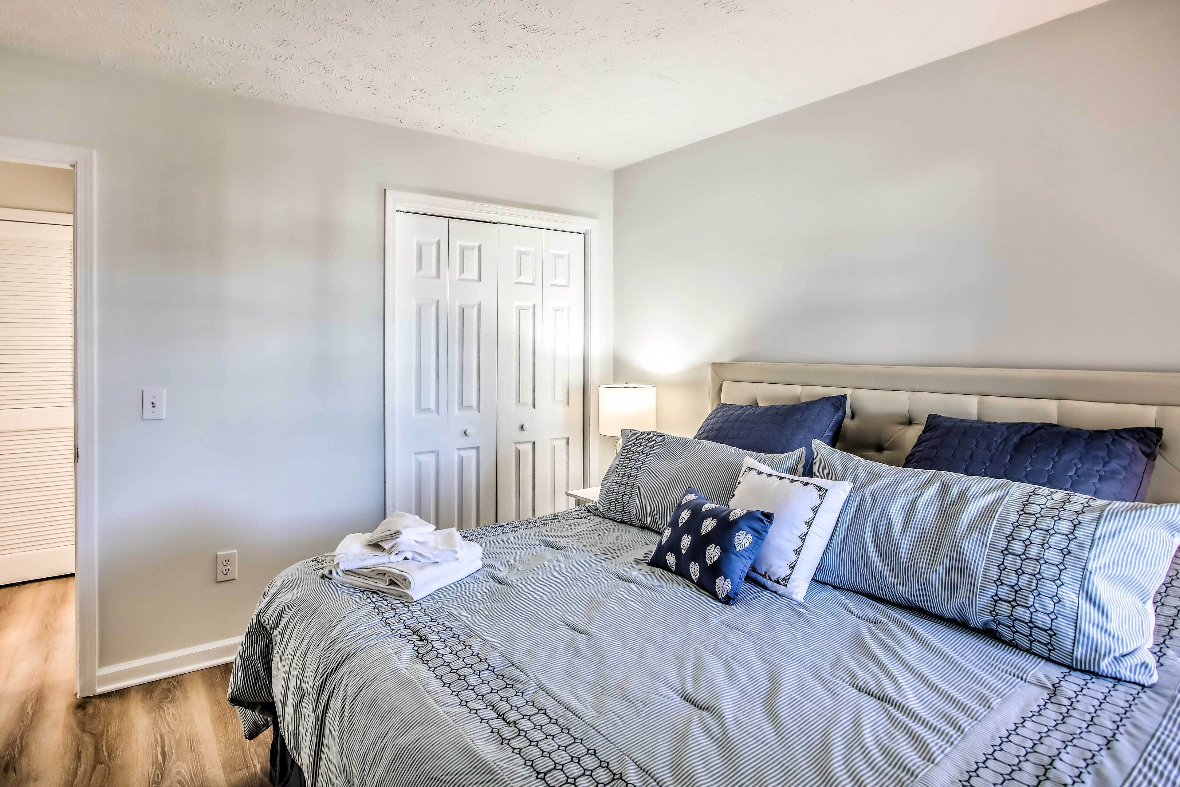 A bedroom with a bed, pillows, a nightstand, and a door.