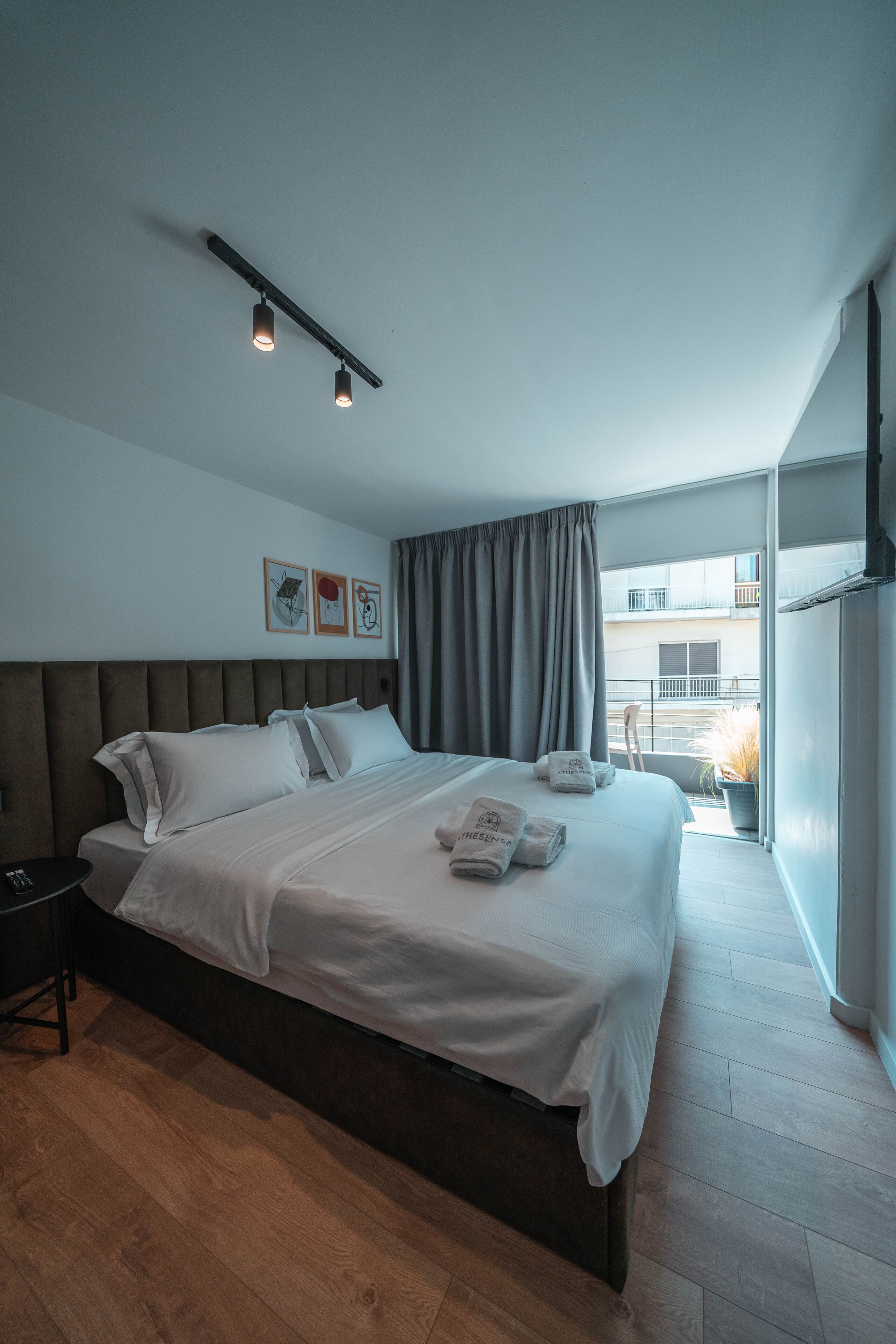 Una camera d'albergo moderna con un letto grande, un comodino, una piccola scrivania e un balcone con vista.