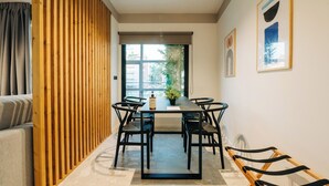 Un comedor moderno con una mesa larga, sillas negras y un separador de madera.