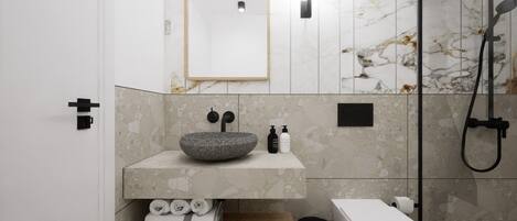 Un baño moderno con lavamanos de piedra, un espejo, ducha y retrete.