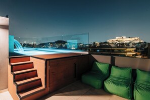 Una piscina al aire libre, sombrillas, sillones reclinables de piscina