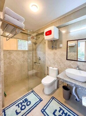 Bathroom features a glass-enclosed shower, toilet, and large sink with a countertop.