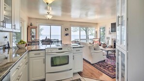 A modern kitchen with white cabinets, a built-in oven, and a large window overlooking a scenic view. - Luxe Chesapeake Bay Getaway < 20 Mi to Annapolis! (Shady Side)