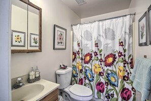 Ein Badezimmer mit Waschbecken, Toilette und Duschvorhang mit Blumenmuster.