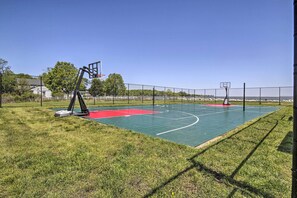 Ein Basketballplatz im Freien mit zwei Körben, umgeben von einem Zaun und einer Rasenfläche.