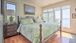 A bedroom with a large bed, a dresser, a window with a view of the sea, and a painting on the wall. - Luxe Chesapeake Bay Getaway < 20 Mi to Annapolis! (Shady Side)